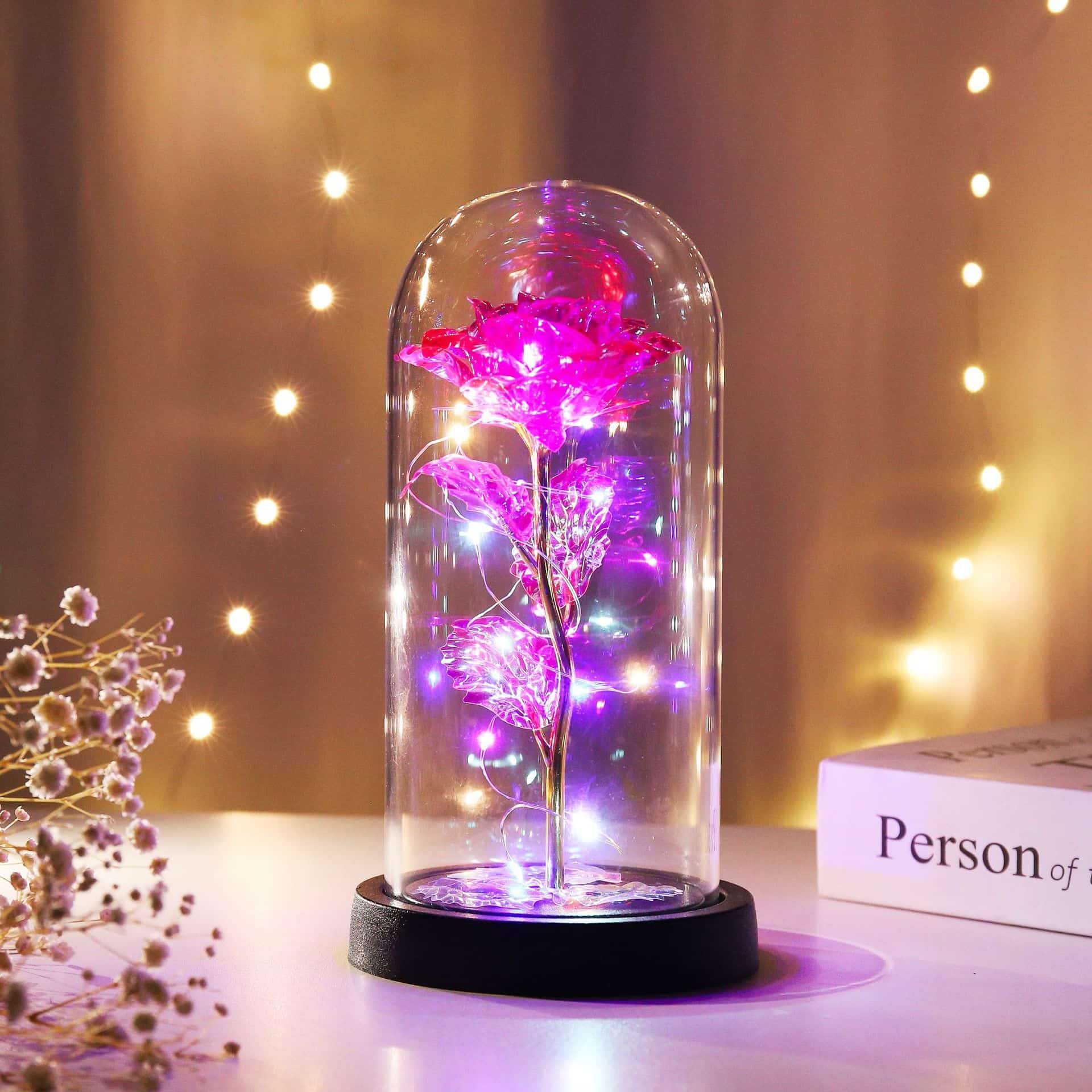 Pink enchanted rose with LED lights, under a glass dome, a beautiful decorative piece.
