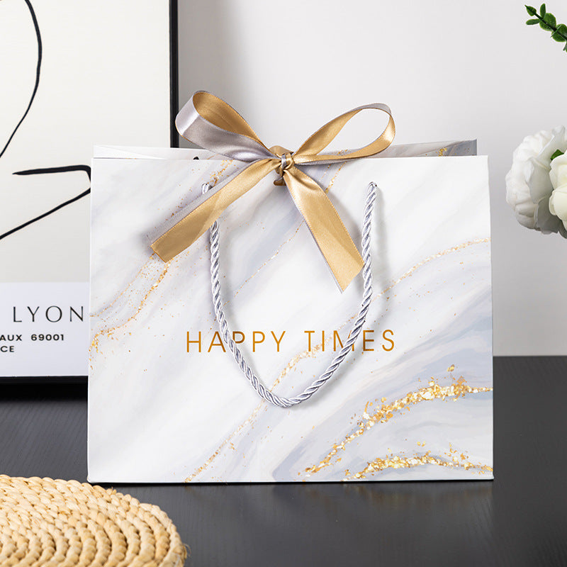 Set of white and pink marble gift bags with gold accents and ribbon bows, perfect for elegant gift-giving.