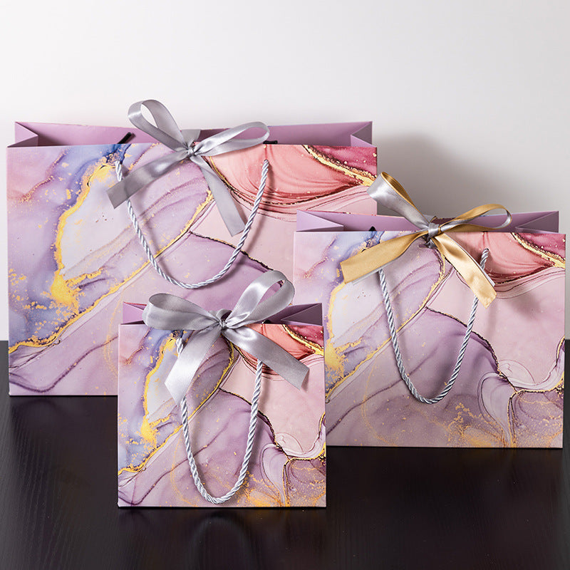 Luxury pink marble gift bag with gold details and ribbon bow, perfect for Valentine's Day or weddings.