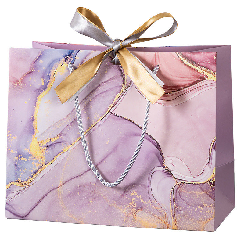 Marble gift bags in white and pink with gold details and satin bows, ideal for Valentine's Day or special occasions.