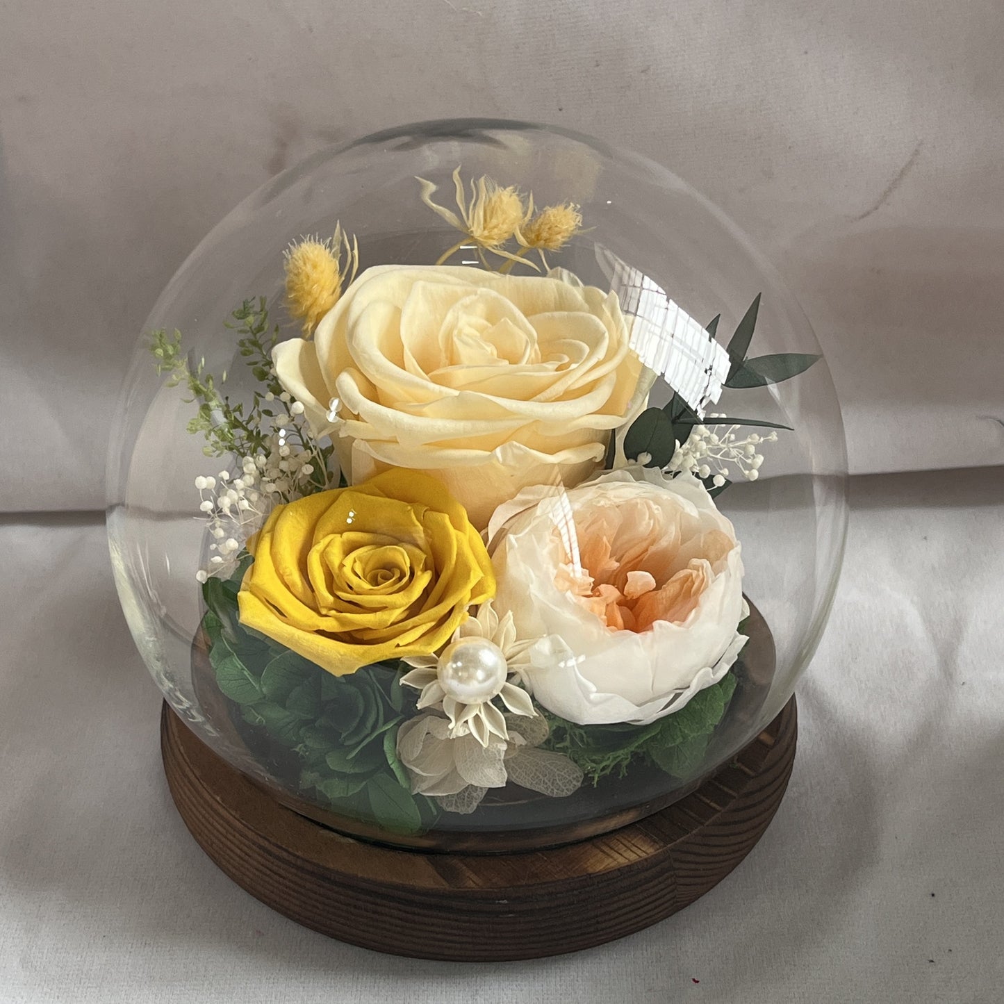 Artificial flower and preserved rose in elegant dome.