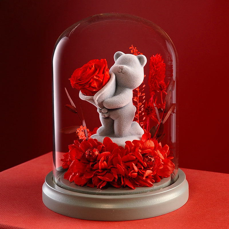 Heart gesture teddy bear with a preserved rose in glass dome, ideal for romantic gestures and special occasions like anniversaries.