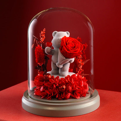 Heart gesture teddy bear with multiple preserved roses inside a glass dome, great for romantic gifts and elegant home decor.